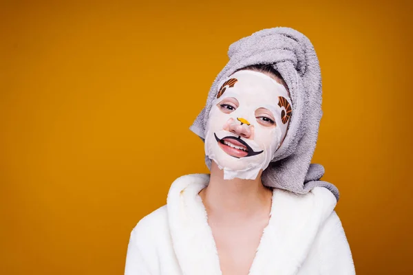 Söt ung flicka med handduk på hennes huvud efter dusch leenden, ansiktsmask med munkorg av djur — Stockfoto