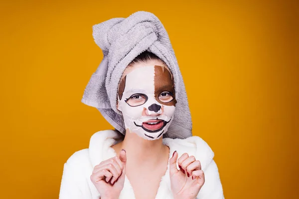 Cute young girl with a towel on her head after a shower smiles, on her face a mask with a muzzle of a dog — Stock Photo, Image
