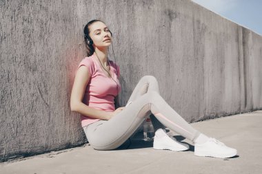 atletik güçlü kız dinlenmek ve açık hava eğitim sonra dinlenmek, heasphones müzik dinlemek ve nefes