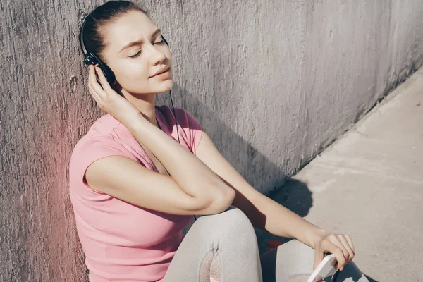 ヘッドフォンで音楽を聞いて難しいトレーニング屋外後休んで若い穏やかな女の子 — ストック写真