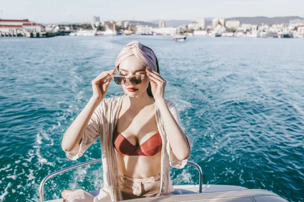 Een luxe rijke vrouw zet op zonnebril, zeilen op de blauwe Caribische zee op een jacht — Stockfoto