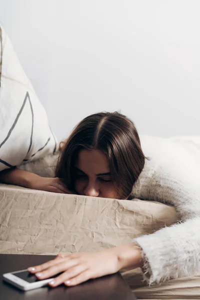 Sonnolenta ragazza si trova a letto, si è svegliata da dietro la sveglia, non vuole alzarsi — Foto Stock