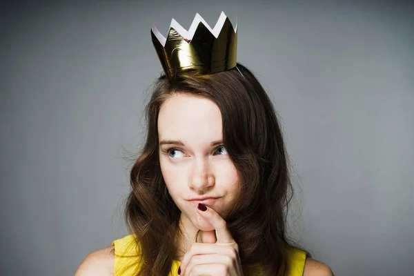 Hermosa joven en un vestido amarillo pensó en algo, en su cabeza una corona de oro — Foto de Stock