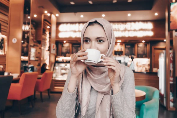 Hijab を厳しく身にかわいいネーチャン オリエンタル カフェに座っているし、香り豊かなコーヒーを飲む — ストック写真