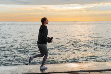 Kendine güvenen güçlü kız deniz dolgu gün batımında, Maratonu için hazırlanıyor çalışır