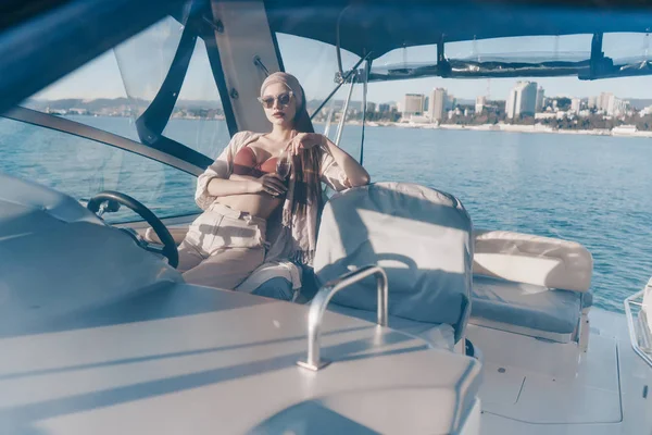Una joven de lujo en gafas de sol se sienta en su yate blanco y navega en el mar Caribe —  Fotos de Stock