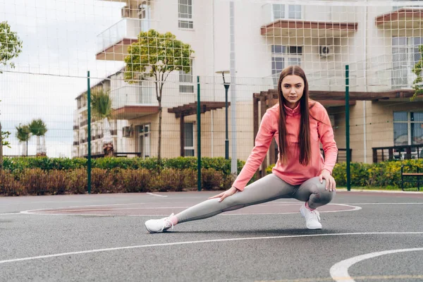 Confiado hermosa chica amasando músculos antes de entrenar en el campo de deportes, quiere perder peso — Foto de Stock