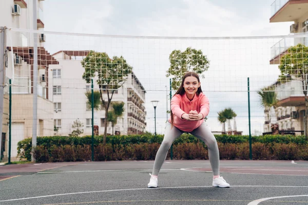 Gelukkig vertrouwen meisje treinen en kruipt, wil een mooi figuur, op het sportveld — Stockfoto