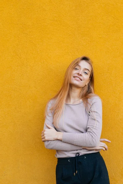 Hermosa chica sonriente con una modelo rubia posando contra una pared amarilla — Foto de Stock