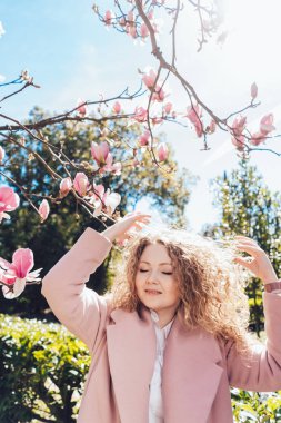 poz ve gülümseyerek, bahar güneş Park'ta yürüyüş kıvırcık mutlu genç kadın