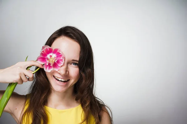 Feliz sonriente joven en vestido amarillo sostiene fragante flor rosa — Foto de Stock