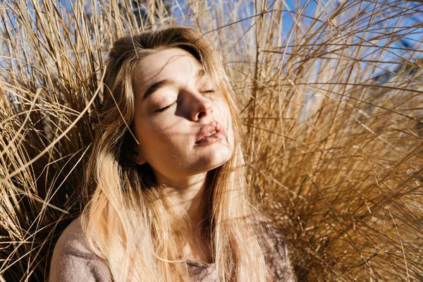 太陽の暖かさを楽しんで美しい金髪少女にあるフィールドに、彼女は目を閉じた — ストック写真