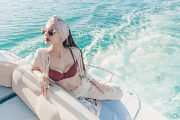 Una mujer rica de lujo en gafas de sol disfruta de un viaje por el mar en un yate blanco —  Fotos de Stock