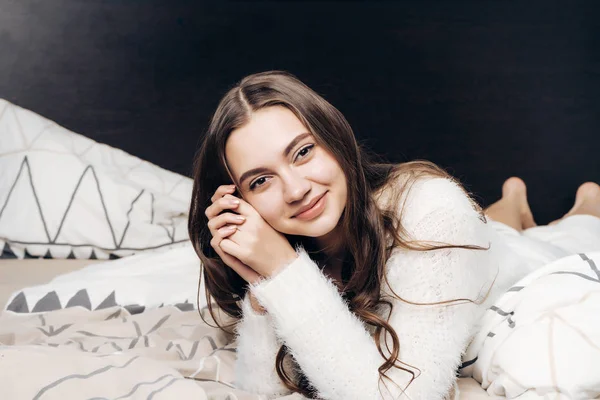 Χαριτωμένο νεαρό κορίτσι με τις πυτζάμες ξαπλωμένη στο κρεβάτι, ανάπαυσης και βλέπουν τα φωτογραφικών μηχανών — Φωτογραφία Αρχείου