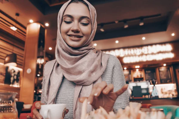 Boldog fiatal muszlim lány fején fejkendő val ebédel, hangulatos kávézót és mosolyogva — Stock Fotó