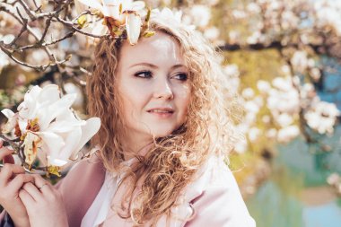 zarif kıvırcık kadın parkta güzel kokulu bir çiçek açan Manolya yanında poz