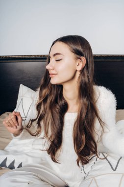 uzun saçlı yatakta sabah erken, uyanık ve germe oturan genç sevimli uykucu kız