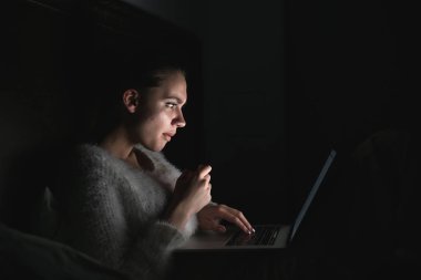 odaklı kız geceleri yatakta yatıyor ve onu laptop korku filmi izler