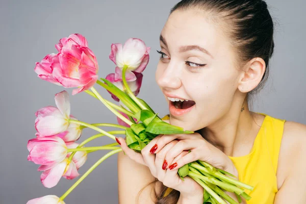 Sarı elbiseli mutlu genç kız pembe güzel kokulu çiçekler elinde tutan, gülüyor ve bahar sahiptir — Stok fotoğraf