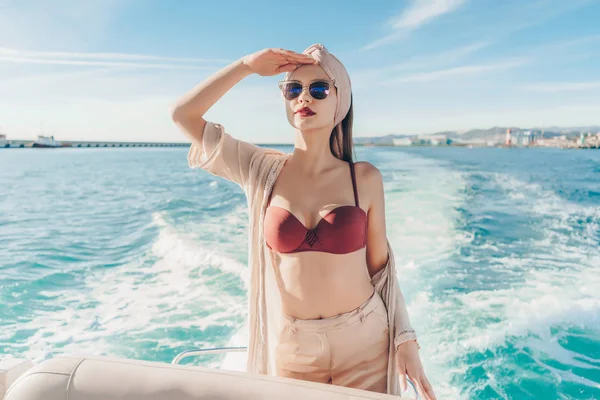 Una mujer rica y elegante en gafas de sol nada en un yate blanco y mira a la distancia, el mar y el calor —  Fotos de Stock