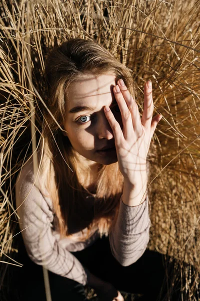 Joven chica de ojos azules modelo rubia cubierto un ojo con su mano, roba en la luz del sol al aire libre — Foto de Stock
