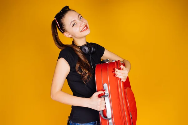 Hermosa chica feliz se va de vacaciones, viaje alrededor del mundo, con una gran maleta roja para las cosas — Foto de Stock