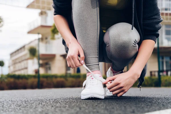 Smal ung flicka binder upp sin skosnören på sina sneakers, tåg på idrottsplanen — Stockfoto