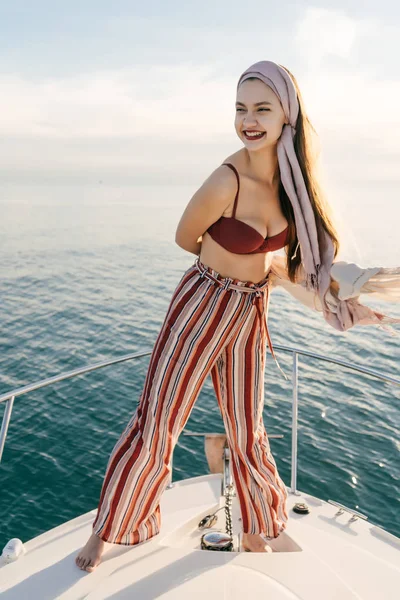Una joven rica en ropa de verano con estilo se encuentra en su yate y disfruta del viaje por el mar —  Fotos de Stock