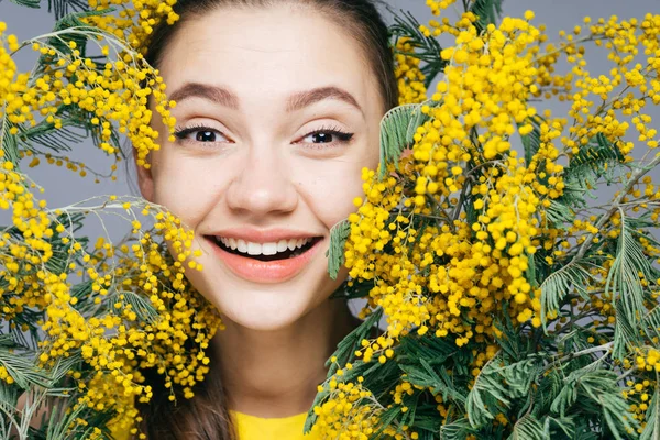 Sevimli genç kız baharda sevinir ve güler, güzel kokulu sarı Mimoza tutar — Stok fotoğraf