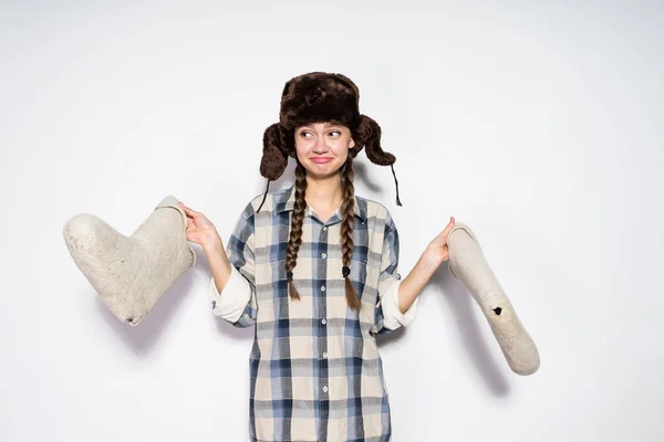 Grappige jong Russisch meisje in een warme bont hoed grijze winter houdt voelde laarzen in handen — Stockfoto