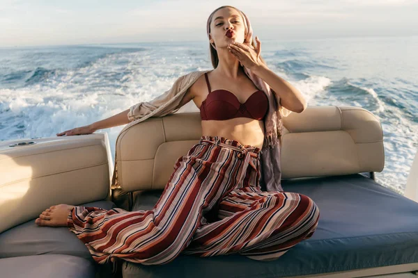 a luxurious rich woman relaxes on her white yacht, sends an air kiss