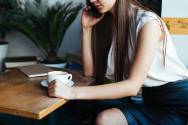 Ofis müdürü arıyor ve masada kahve içiyor.