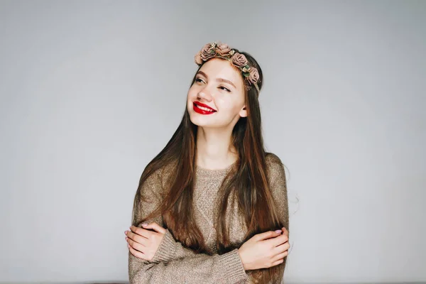 Chica de pelo oscuro en una corona en la cabeza, sonríe alegremente en un estudio de color claro — Foto de Stock