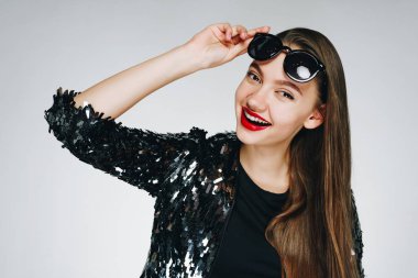 Kız gözlüğünü eliyle alnının üzerine tutarak muzaffer bir şekilde gülümsüyor. ışık arkaplanı