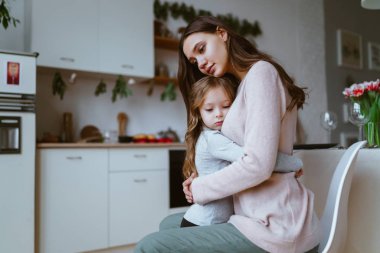 Anne, mutfakta kızına sarıldı. Her iki yüzün de hüzünlü bir ifadesi var.