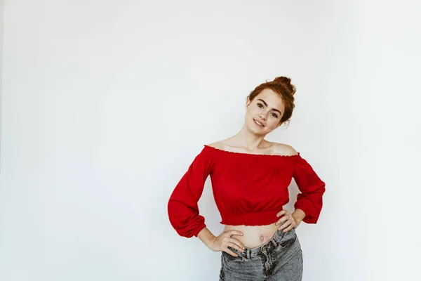 Menina com o cabelo reunido em um pão no topo de sua cabeça fica em um estúdio brilhante akimbo — Fotografia de Stock