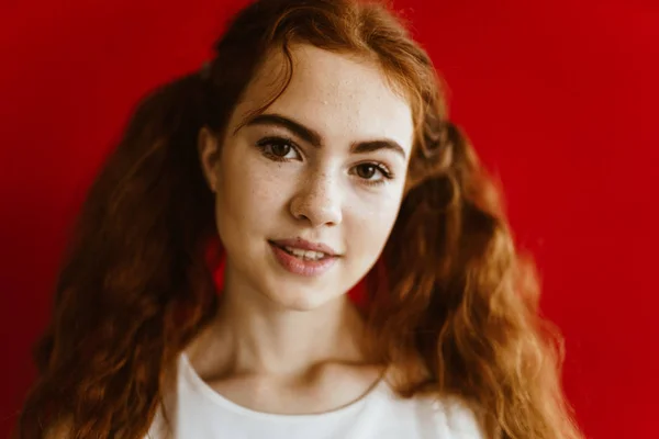 Beleza de olhos castanhos ruivos - a menina olha com um sorriso encantador para a câmera. fundo marrom vermelho — Fotografia de Stock