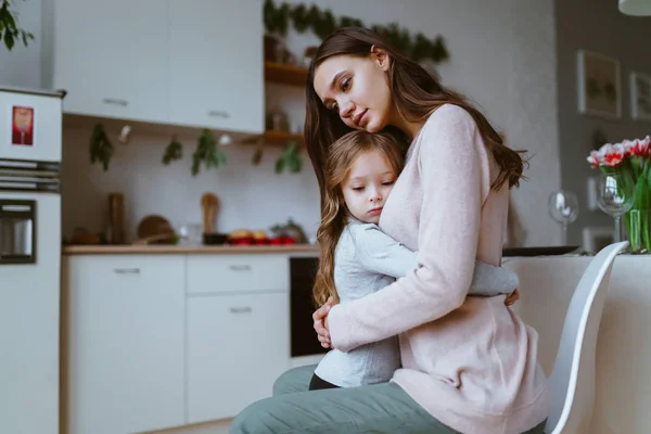 Maman étreint sa fille dans la cuisine, les deux visages ont une expression de tristesse calme ou de tristesse — Photo