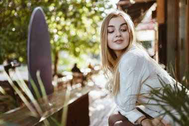 Kız omzunun üstünden bakıyor ve arka planda bir sokak kafesi var.