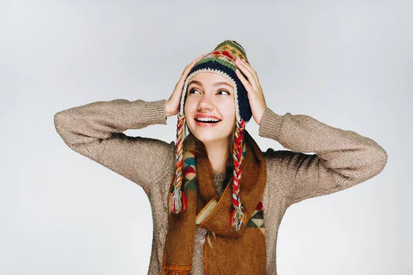 Dívka v teplém klobouku národů severu drží hlavu v dlaních a radostně se usmívá — Stock fotografie