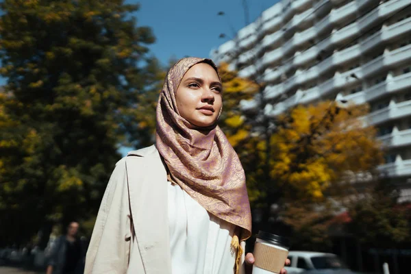 Muslim woman on a city street holds coffee — Stock Photo, Image