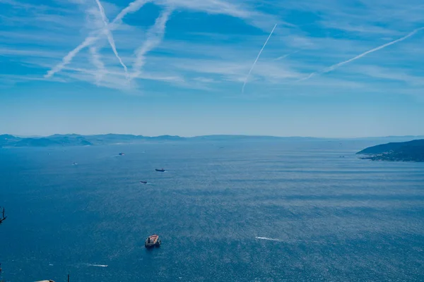 Lujoso mar azul con barcos flotantes y un cielo azul salpicado de pistas de avión —  Fotos de Stock
