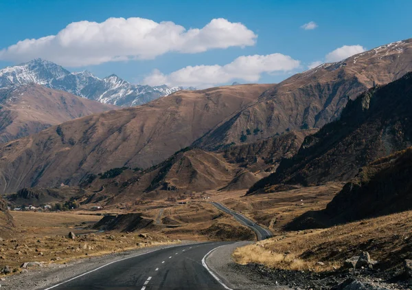 Scenery. view of the highway stretching into the dark gray mountains in the distance covered with snow — Stock Photo, Image