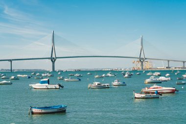 Boğaz üzerinde bir köprü ve suyun altında çok sayıda tekne ve tekne var.