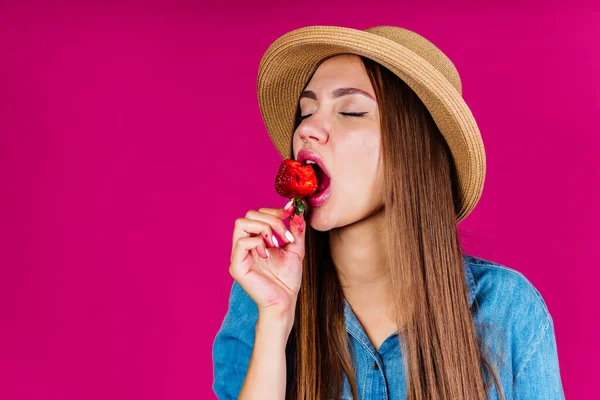 Amante de la fruta con placer y lujuria, cerrando los ojos pone fresa en su boca — Foto de Stock