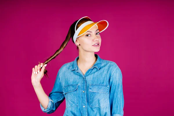 La ragazza nella visiera torto i capelli lunghi in un fascio e tirato lateralmente guardando lo schermo — Foto Stock