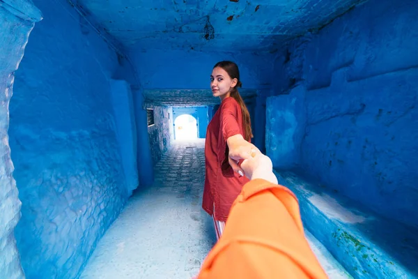 En el marco de la mano sosteniendo la mano de una chica que va más profundo en el pasillo en la ciudad azul de Marruecos — Foto de Stock