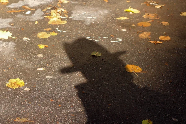 一个人的影子在帽子在秋天的沥青 — 图库照片