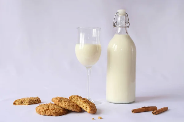 milk in a transparent glass bottle with a lid yoke, milk glass, homemade oatmeal cookies, cinnamon, white background