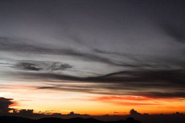 Gün batımı (gündoğumu) dağlarda, güneşin bulutların renkli gökyüzü arkasında